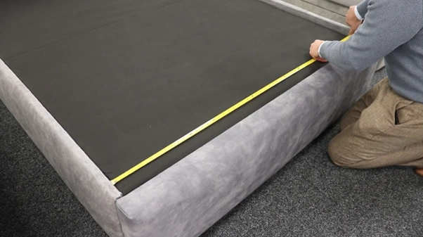 Someone measuring a bed frame with a tape measure